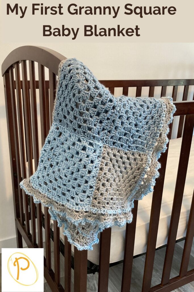 blue and grey granny square blanket on the side of crib